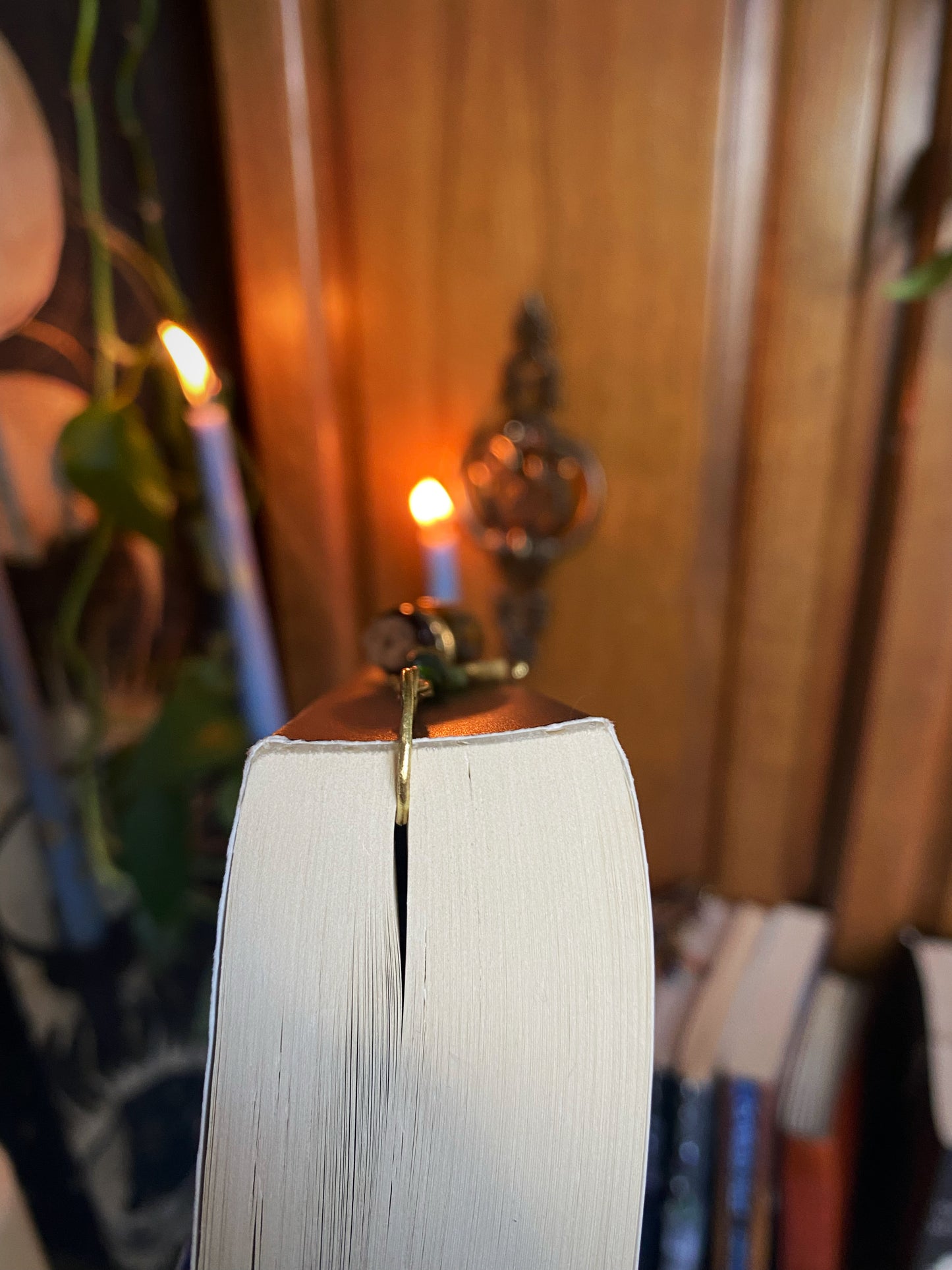 top-down view of clised book with metal bookmark and candles in the background