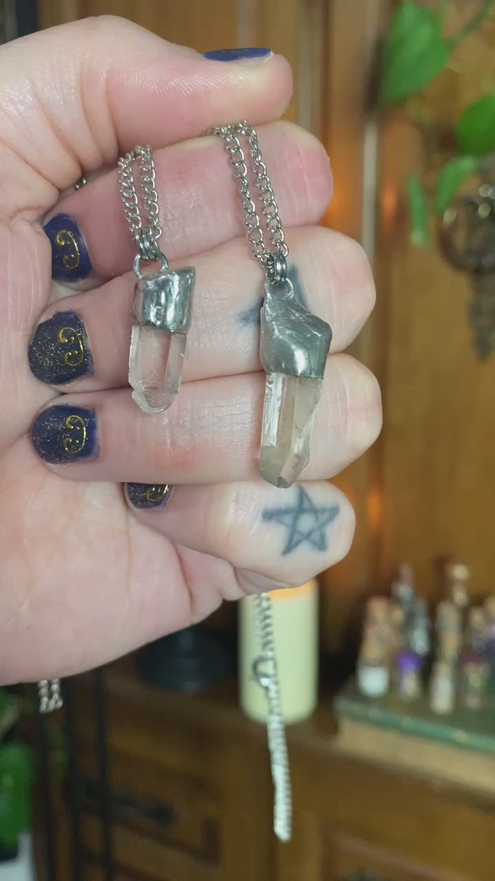 short video of a hand holding two simple quartz pendants