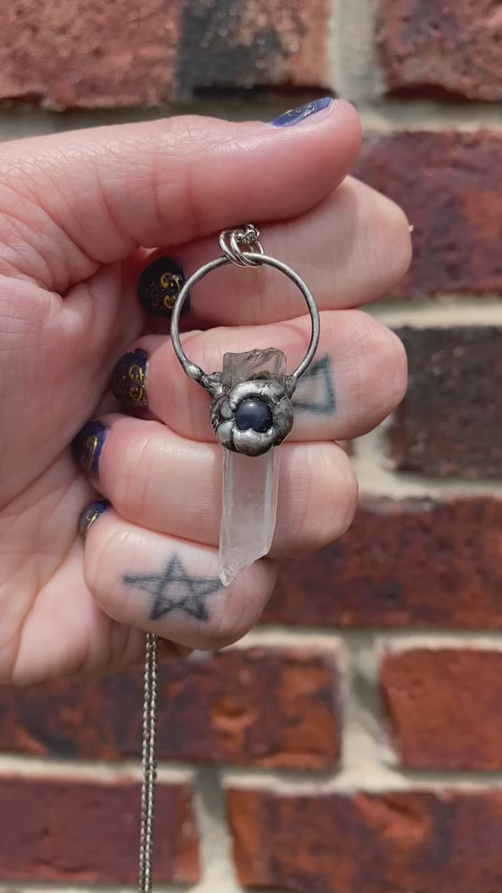 short video and holding a quartz + sodalite pendant in front of a brick wall